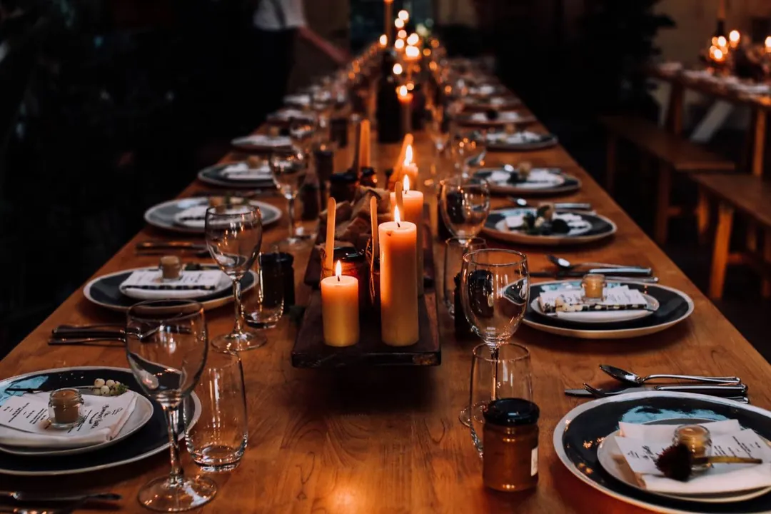 A long banqueting table laid for a wedding feast, lit by candles