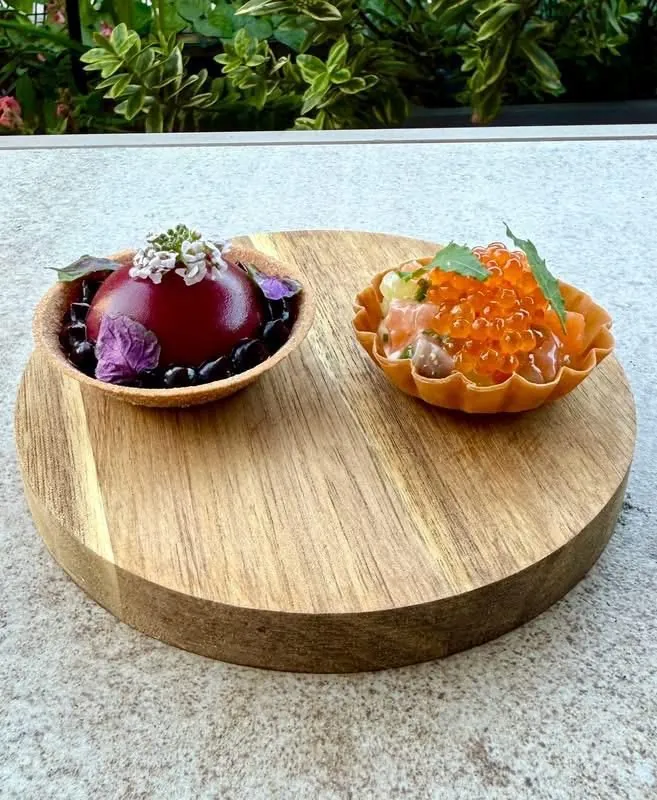 Two canapés on an oak board, one topped with roe