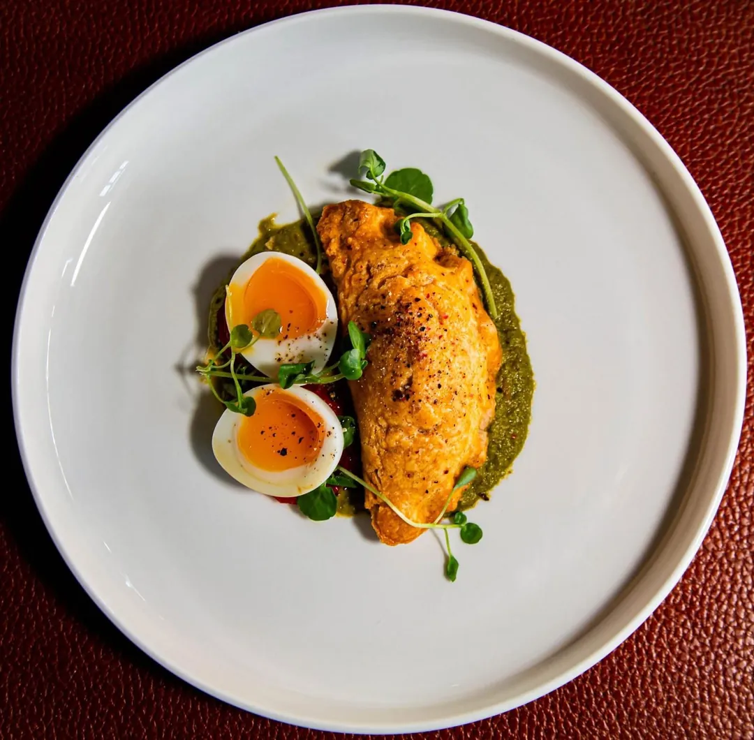 A plated dish with a soft boiled egg and a green herb sauce