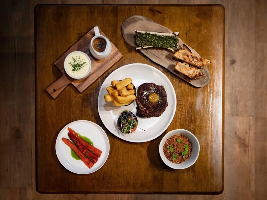 Seen from above, a sharing spread of small plates on a wooden board